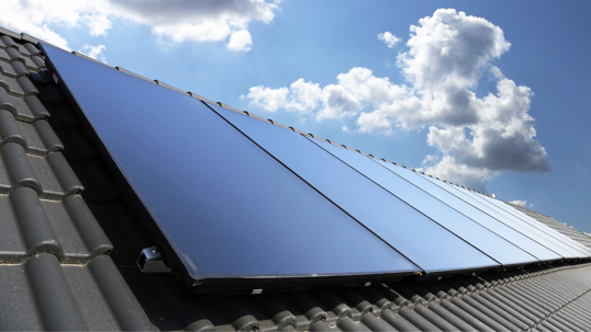 Rooftop solar panels installed on a home under a sunny sky, representing clean energy and renewable power.