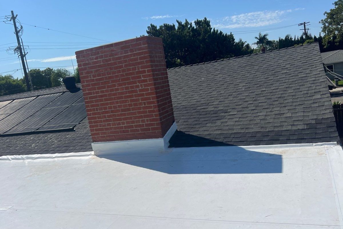 White single-ply roof with a cricket built behind a brick chimney in Long Beach