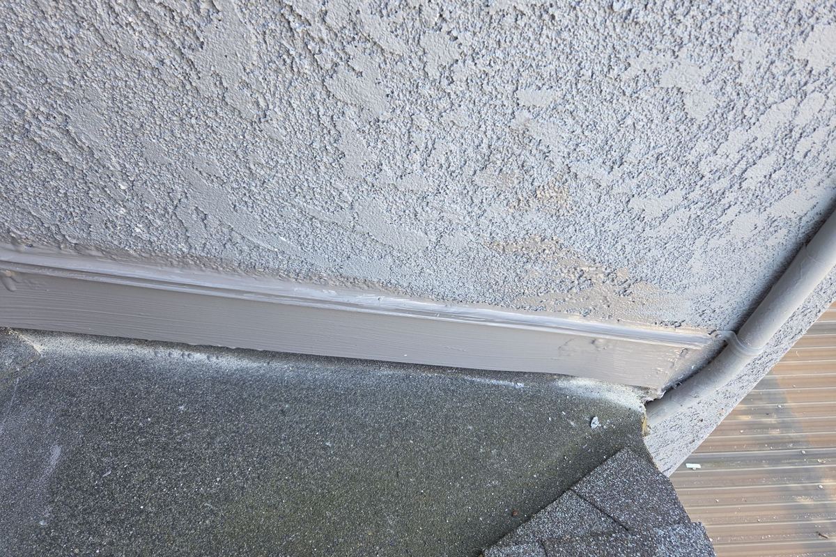 New roof-to-wall metal flashing where a roof meets a stucco wall in Long Beach